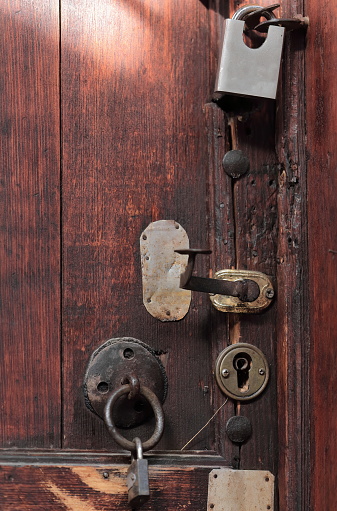Set of locks, handles, metal plates and padlocks on a closed old wooden door with nails on it that reveal previous closing devices, of a house in the Old Bazaar-Pazari i Vjeter area. Kruja-Albania.