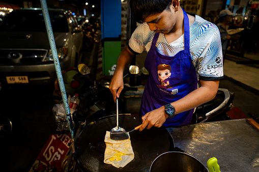 A street food vendor makes roti on the street in Chiang Mai, Thailand.