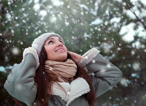 Young woman in a winter forest with snowflakes on her face close-up