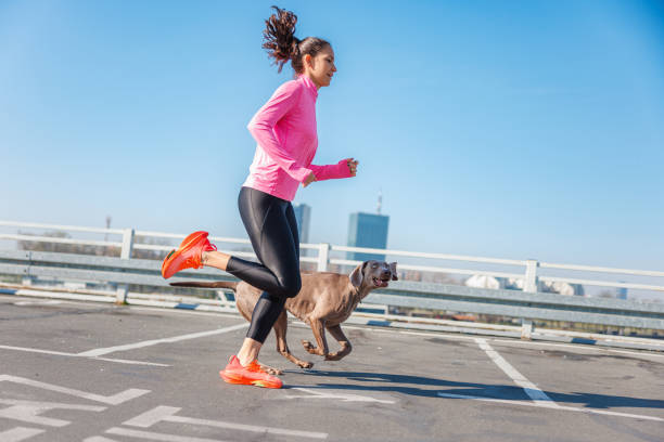 istock Active woman and her dog running on empty parking garage under the clear sky 1807490707