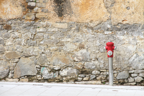 hydrant with red cap against old house wall