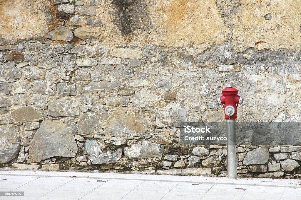 hydrant hydrant with red cap against old house wall Building Exterior Stock Photo