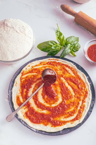 istock Raw dough for pizza with ingredient: tomato sauce 1807503178