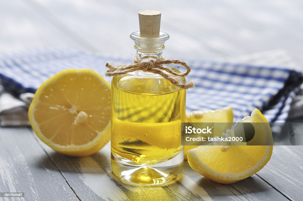 lemon oil in a glass bottle lemon oil in a glass bottle with fresh ëåìîí îí wooden background Aromatherapy Stock Photo