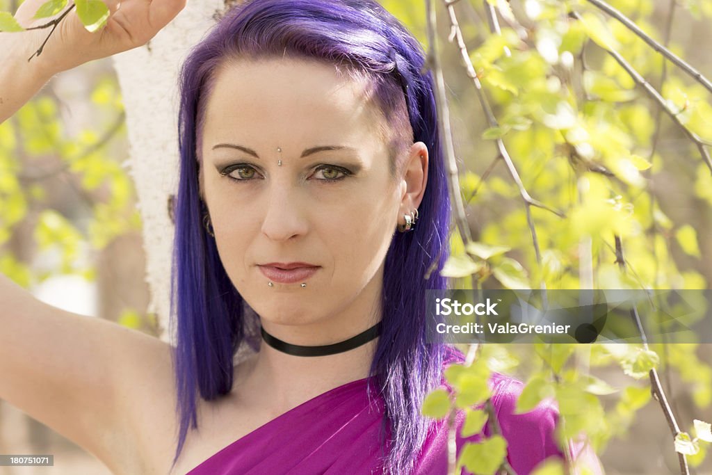 Purple haired woman leaning on birch tree. "Horizontal outdoor shot of woman with hand over head, leaning against tree." 30-34 Years Stock Photo