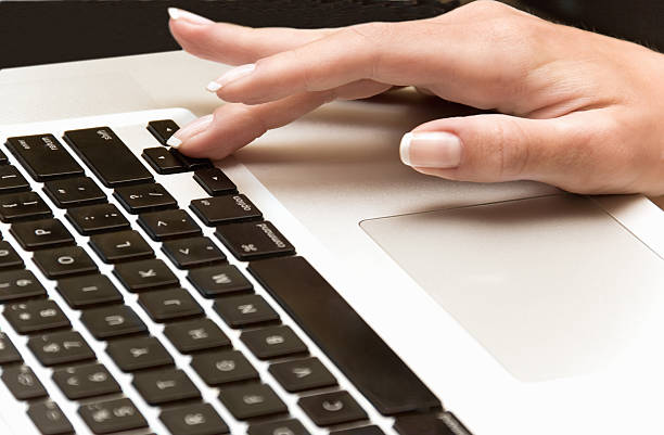 fêmea mãos digitando no teclado de um laptop - workbook notebook pen ballpoint pen - fotografias e filmes do acervo