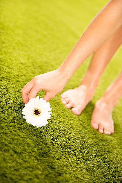 Woman picking up blossom from grass in park