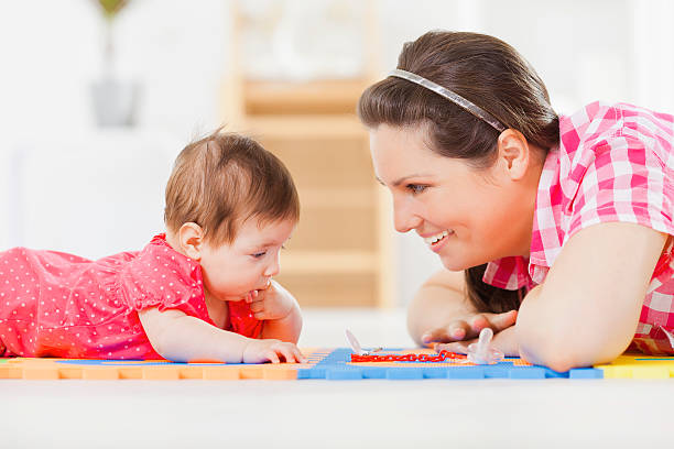 Baby lying on the floor with mother stock photo