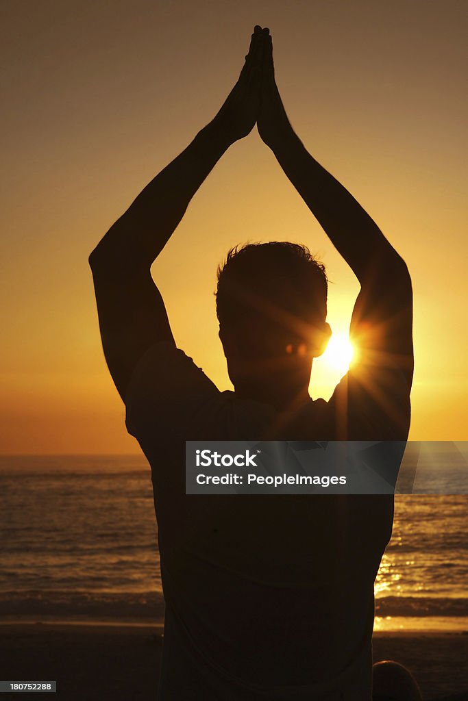 Saluting the sunrise Silhouette of a man against the sunset with his arms raised in a yoga pose 20-29 Years Stock Photo