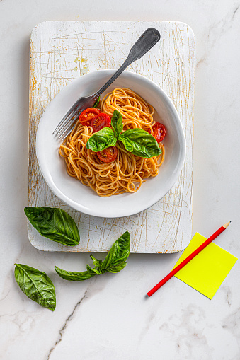 Pasta, spaghetti with tomato sauce and fresh basil in a bowl