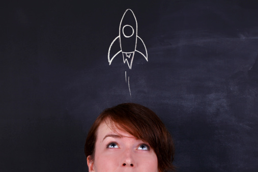 Female against blackboard with chalk rocket