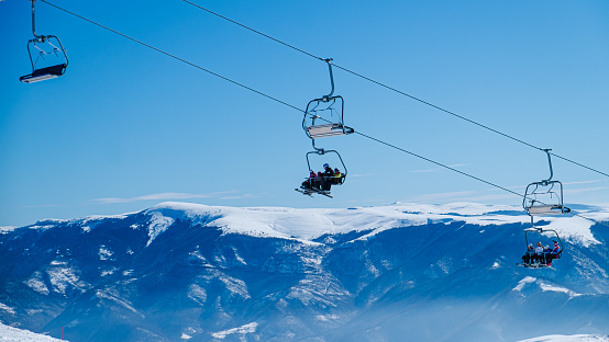 Ski lifts moving above the snowcapped mountain peaks on a beautiful clear day in winter