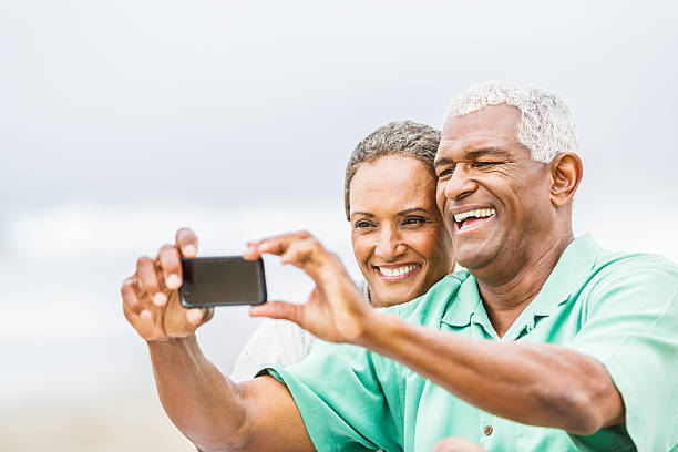 istock Senior couple having fun with smart phone on beach 180754157