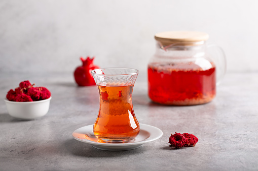 Pomegranate tea in glass cup on gray background. Traditional Turkish fruit herbal tea.