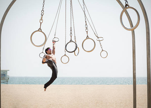 Man on Santa Monica Traveling Rings "Young man on the Traveling Rings on Muscle Beach in Santa Monica, California" muscle beach santa monica stock pictures, royalty-free photos & images