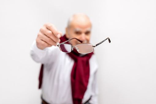 Vision correction and treatment. A mature man throws away his glasses after vision treatment. A happy man with good vision. Ophthalmic problems, poor vision in old age, macular degeneration