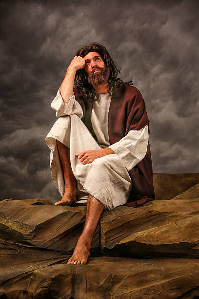 istock Jesus Sitting on rock looking up 180754580