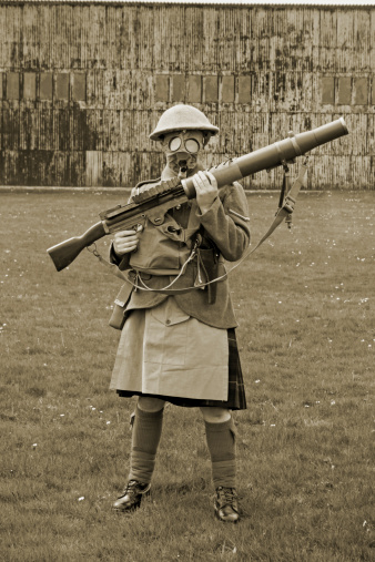 WW1 Scottish soldier stands wearing his gas mask and vickers machine gun.Picture has been aged to give the feel of a vintage photograph.