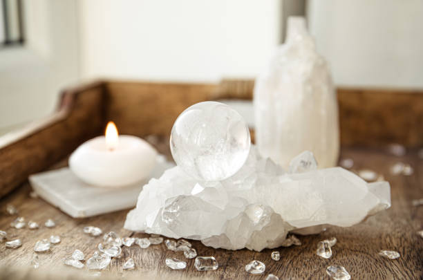 Gemstone sphere or crystal ball known as crystallum orbis and orbuculum which is the beacon of peace and harmony in home environment. Natural clear quartz ball on quartz geode on wood tray.