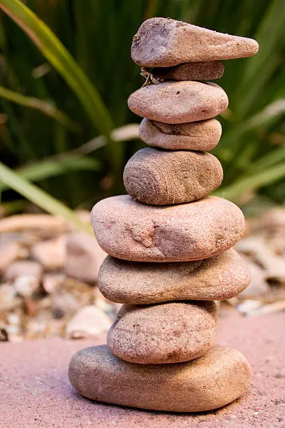 This photo shows a stack of rocks against a backdrop of a green garden.