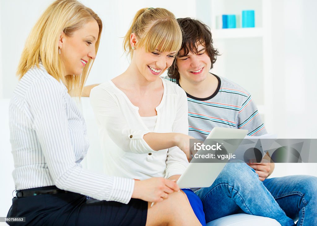 Cheerful Young Couple Meeting with financial advisor. Cheerful young couple meeting with financial advisor. They are talking about loans. Business woman presenting them an offer on laptop. 20-29 Years Stock Photo