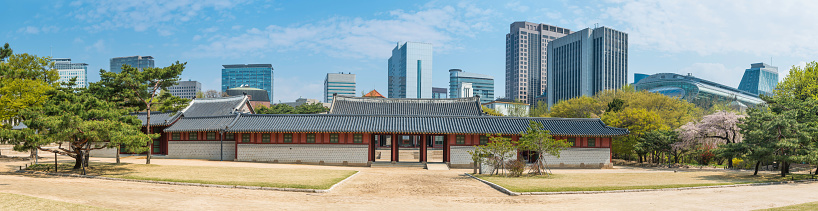 The historic pagoda roofs and traditional wooden pavilions of Deoksugung palace set in the tranquil courtyards and carefully manicured parkland overlooked by the modern architecture and skyscrapers of downtown Seoul, Korea's vibrant capital city. ProPhoto RGB profile for maximum color fidelity and gamut.