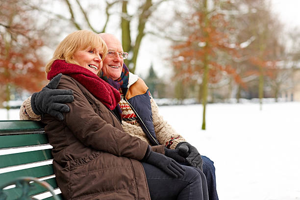 Elderly couple sitting on a bench at snow park