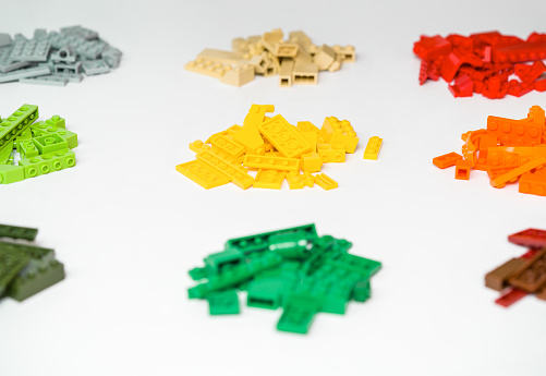 Piles of many various colored stackable plastic toy bricks on white background. Educational toy for children.