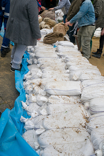 Many volunteers helpers at the building of flood protection with stacking of sandbags
