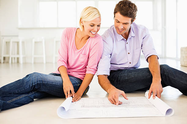 istock Happy Couple Looking Through Blueprint At Home 180762007