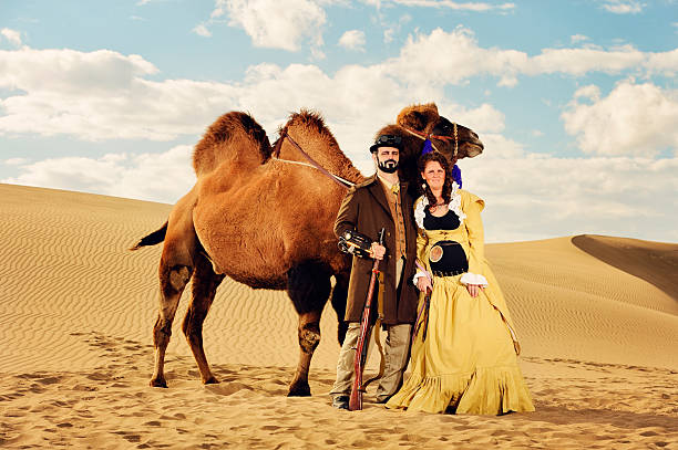 coniugi steampunk coppia un viaggio infinito con il cammello nel deserto - turismo di eco foto e immagini stock
