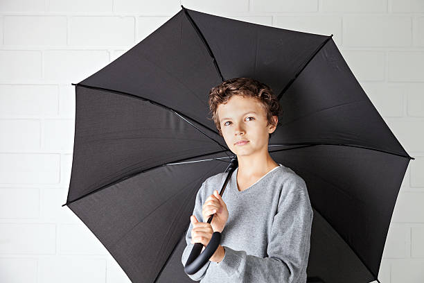 istock Teenage boy and a black umbrella 180763425