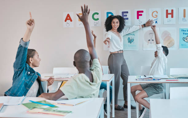 istock Question, learning and education at school with kids hands raised to answer alphabet assessment. Classroom, learners and tutor teaching a summary information in a class with smart and clever group 1807675606