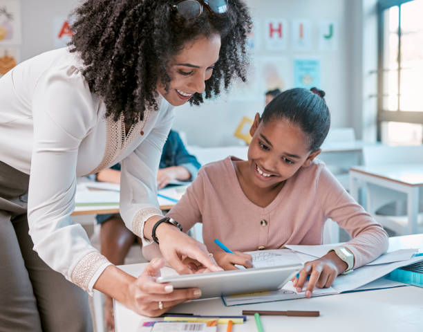 istock Tablet education, teacher and kid learning, writing and digital support, helping and classroom mentor. Black woman or person teaching child on technology in English, language or creative development 1807678370