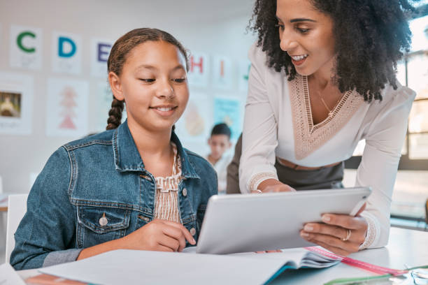 istock Education, girl or teacher and student on tablet for exam learning, assessment idea or scholarship support. Research, school or kid in classroom on tech for information help, search or grade analysis 1807678373