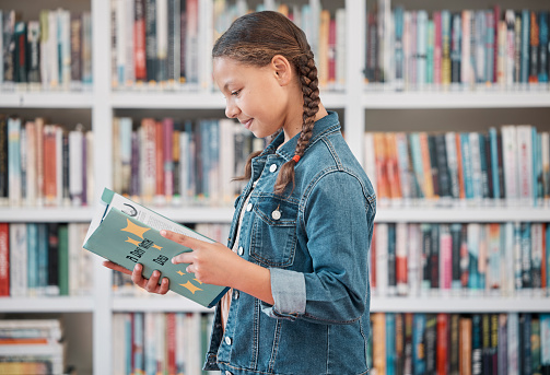 Books, education or child in a library reading for knowledge or development for future growth. Scholarship, girl or school student with a happy smile studying or learning information in a fun story