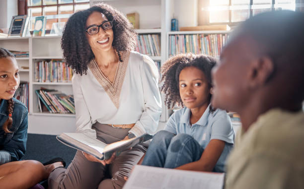 istock Storytelling, teacher or students with talking in a library asking questions for learning development. Education, kids or children listening to a black woman speaking on fun books at school classroom 1807684688