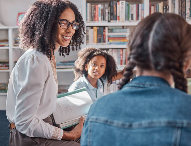istock Teacher, storytelling or children in a library for learning development, reading skills or growth. Happy smile, kids or students listening to a black woman asking for feedback on fun books at school 1807684702