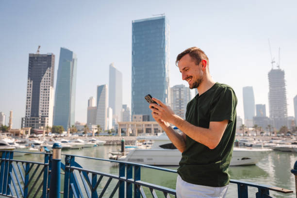 istock Young Caucasian man talking on the phone while walking by the sea in Kuwait 1807686321