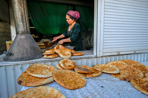 Dushanbe, Tajikistan - November 13, 2023: A woman making bread at the Mehrgon Market in Dushanbe, Tajikistan.