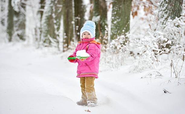 Little girl plays with shovel in snow Little girl plays with a shovel in the snow. She walks in the Oak Alley. digging photos stock pictures, royalty-free photos & images