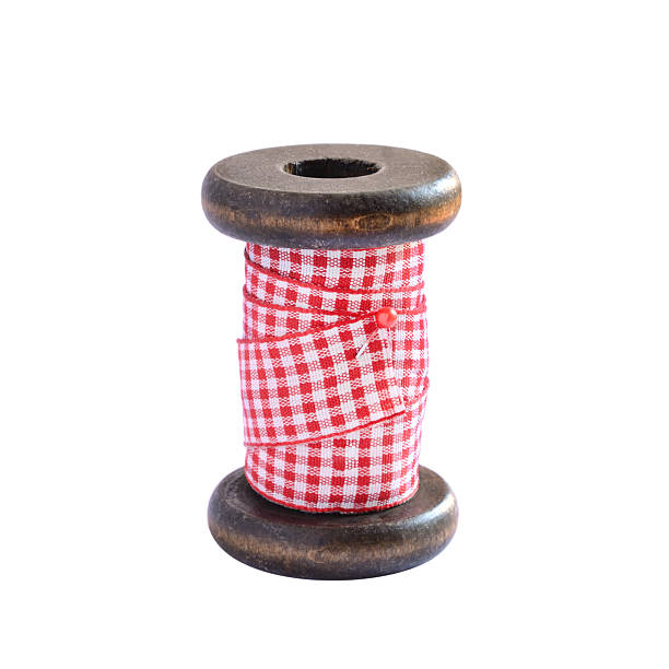Checky red ribbon spool on white background Vintage wooden spool with red and white ribbon on white background wooden spool stock pictures, royalty-free photos & images