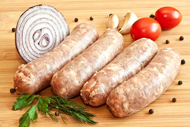 istock Uncooked sausages with vegetables on the chopping board 180770844