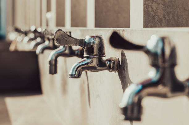 una hilera de grifos y fregaderos de acero inoxidable - agua grifo fotografías e imágenes de stock