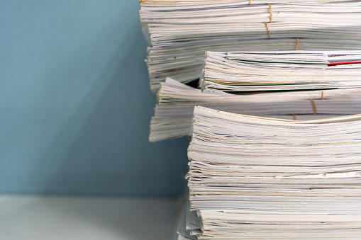 Close-up Stack of papers, documents and files. Large stack of files, documents, paperwork on desk. Paperwork: messy stack of files, documents and papers in office.