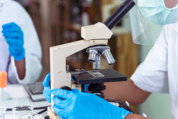 istock Indian Scientist man look into Microscope research in science laboratory. Asian biochemistry scientist using microscope in laboratory chemistry labs. Covid-19 medical research scientific experiment 1807740424