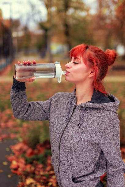 istock Redhead woman drinking water from bottle in park 1807743614