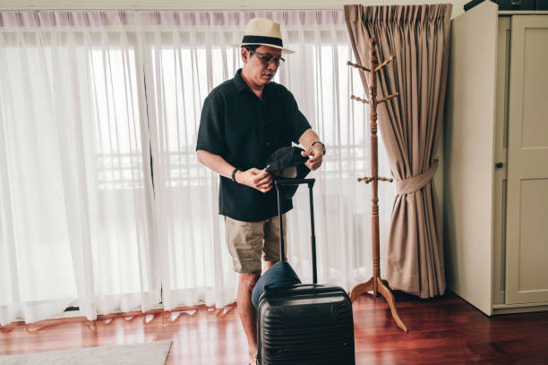 自宅で旅行のためにスーツケースを梱包する年配のアジア人男性 - pulling a name from a hat ストックフォトと画像