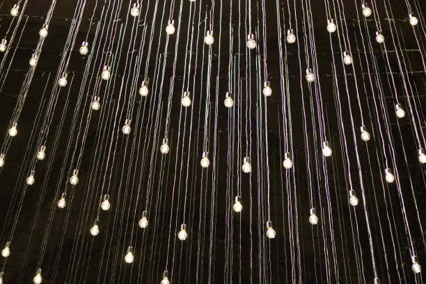 Masses of light bulbs hanging in mid air, surrounded by darkness