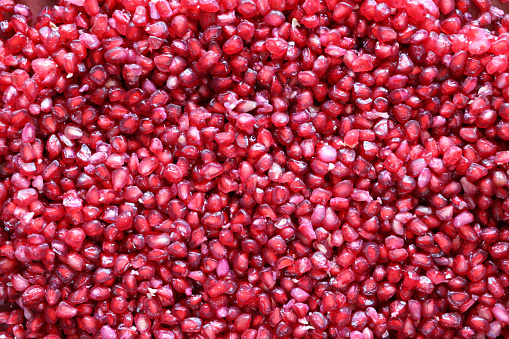 Stock photo showing a close-up, elevated view of healthy eating image of pomegranates (Punica granatum) seeds displaying red flesh (arils) encasing seeds.